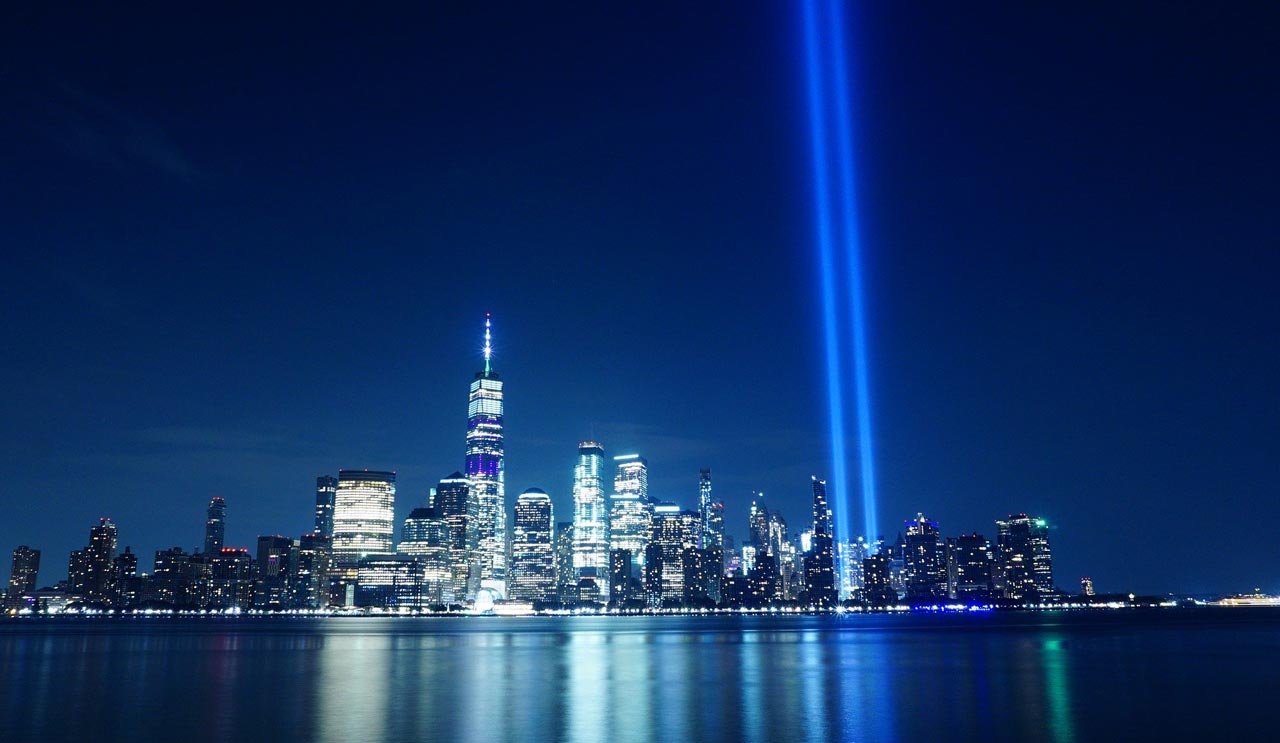 blue lights shine against the night sky where the twin towers once stood