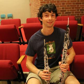 David Brinkley sitting in Buckley Recital Hall, holding two oboes