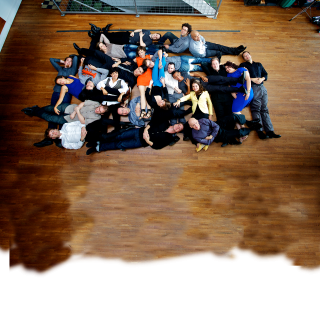 Overhead shot of members of the International Contemporary Ensemble lying down on a shiny wooden floor 