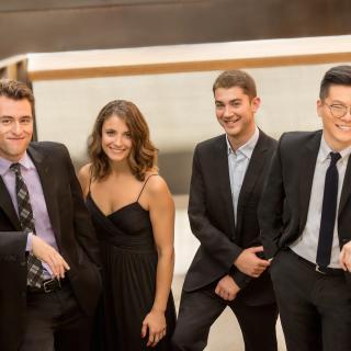 The four members of the Dover Quartet standing in a row and smiling