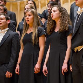 Choral Society students standing on the Buckley Recital Hall stage, dressed in formal black