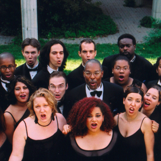 Nathaniel Dett Chorale standing together and singing outdoors, wearing black dresses and suits