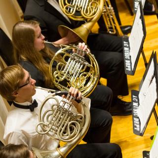 ASO members playing French horns in front of music stands on the Buckley Recital Hall stage