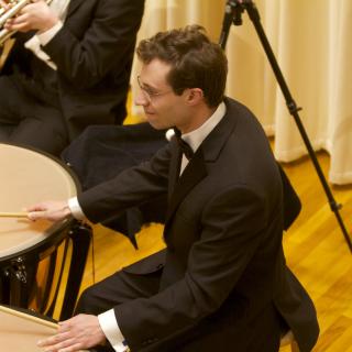 Young man in a suit and tie playing timpani on the Buckley Recital Hall stage
