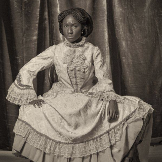 Black and white photograph of the artist in Victorian dress performing the role of Sarah Forbes Bonetta.