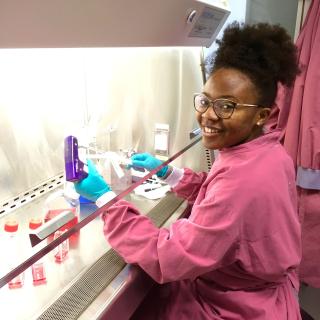 Holda Anagho ’14 smiling while working with equipment in a laboratory