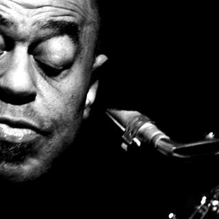 Black-and-white closeup of Archie Shepp with his eyes closed, holding a saxophone