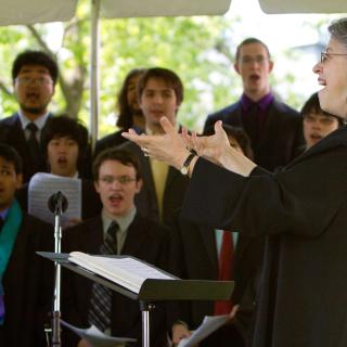 Choral Society members singing outdoors at Commencement, conducted by Mallorie Chernin