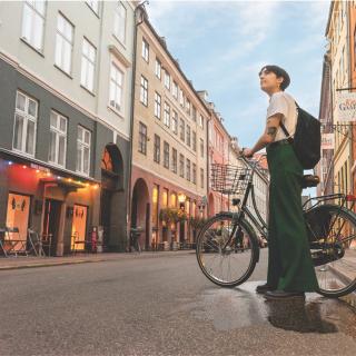 photo of a DIS Copenhagen student, standing next to their bike and looking around the Copenhagen city center