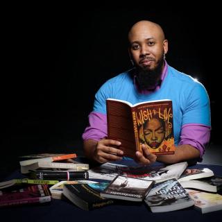 Photo of Dr. Callier sitting behind a pile of books