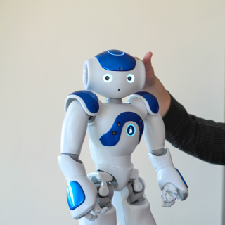 Robot standing on table with supportive hand behind it