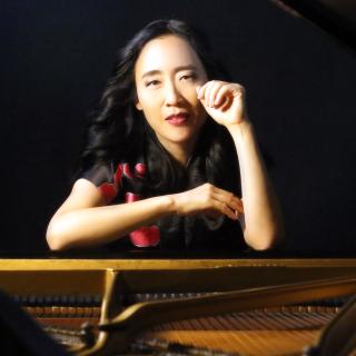Portrait of Helen Sung sitting at an open piano