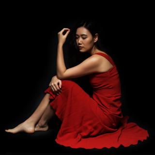 Jihye Lee, seated and barefoot, wearing a red dress