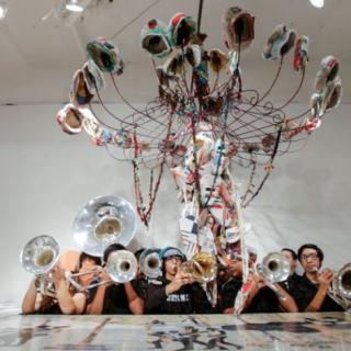 Musicians with horns under hanging artwork