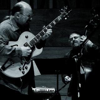 Black-and-white image of the Michael Musillami Trio +2 playing instruments