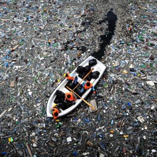 Boat with people collecting plastic from polluted ocean