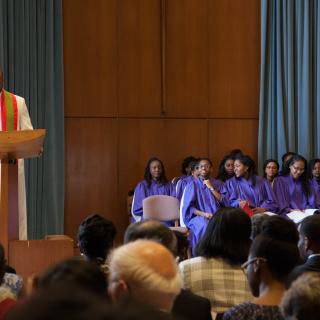 Rev. Tim Jones '04 preaches at the Bi-Semester service as the gospel choir looks on