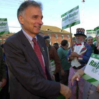 Ralph Nader outdoors among people holding "Ralph Nader for President" signs
