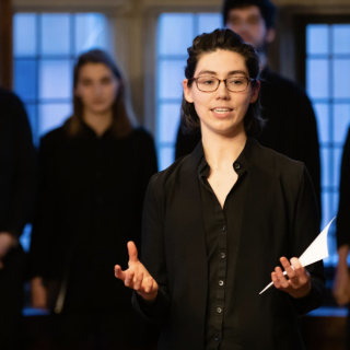 Photograph of Ellen Mutter '18 conducting the Amherst College Choral Society in the Rotherwas Room at the Mead Art Museum. Photo by Jiayi Liu.