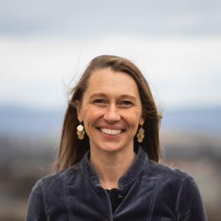 Dr. Stephanie Stockwell wearing a dark blue jacket and dangly earrings and smiling at the camera