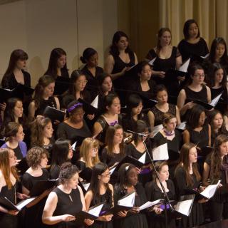 Women's Chorus standing on stage, dressed in black