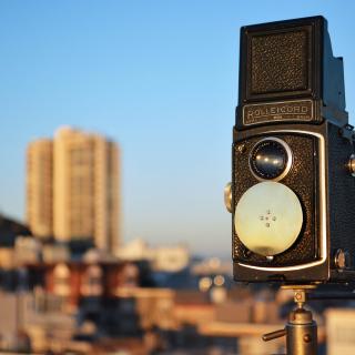 A camera mounted on a pole, with blue sky and a cityscape in the background
