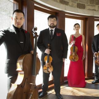 The Parker Quartet standing at a series of sun-lit windows and holding their instruments