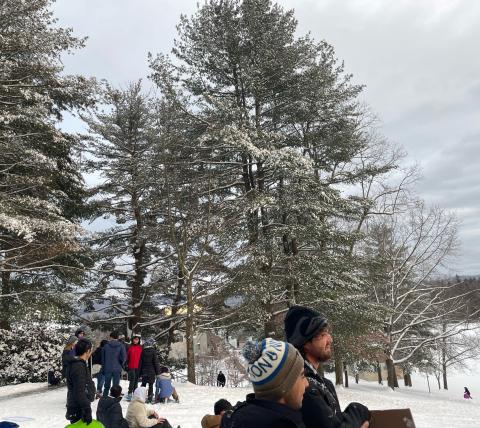 A few students look out over a snowy Memorial Hill
