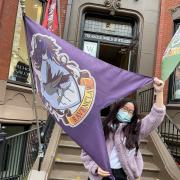 Grace stands in front of a Harry Potter shop holding up a Ravenclaw flag. 