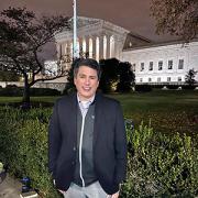 A man standing in front of the Supreme Court at night