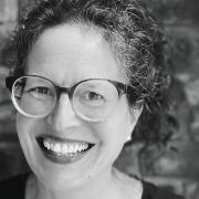 A black and white photo of a woman was glasses and broad smile