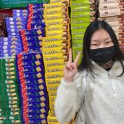 Friend in front of a pile of snack boxes in Hmart. 