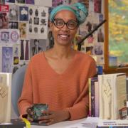 Sonya Clark sits in her art studio with sculpted books next to her