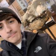 Picture of Matt next to a fossil in Beneski for a geology class project