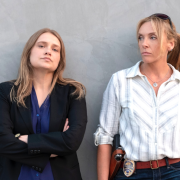 Two women leaning against a wall with intense looks on their faces