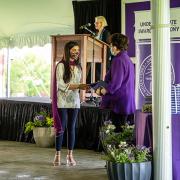 A student getting handed an award by President Biddy Martin outside in a tent