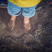 A kids standing with their feet in the mud